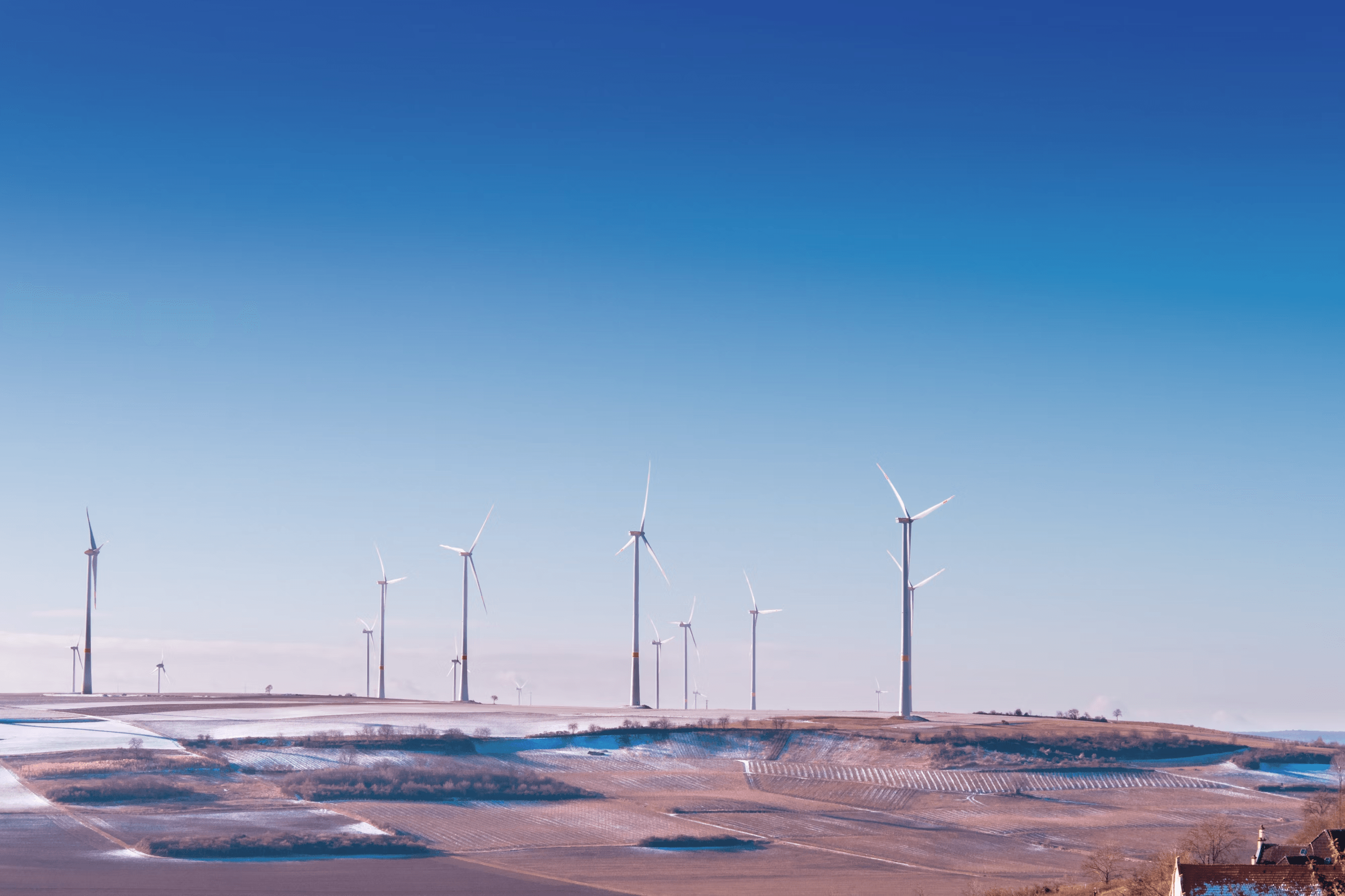 Picture of wind turbines on a hill with blue skies in the background.